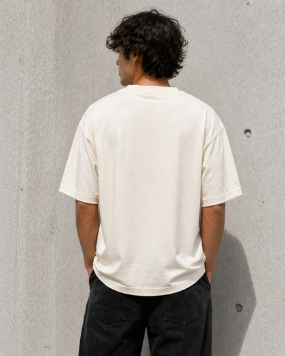 Person wearing a plain white t-shirt against a gray concrete wall