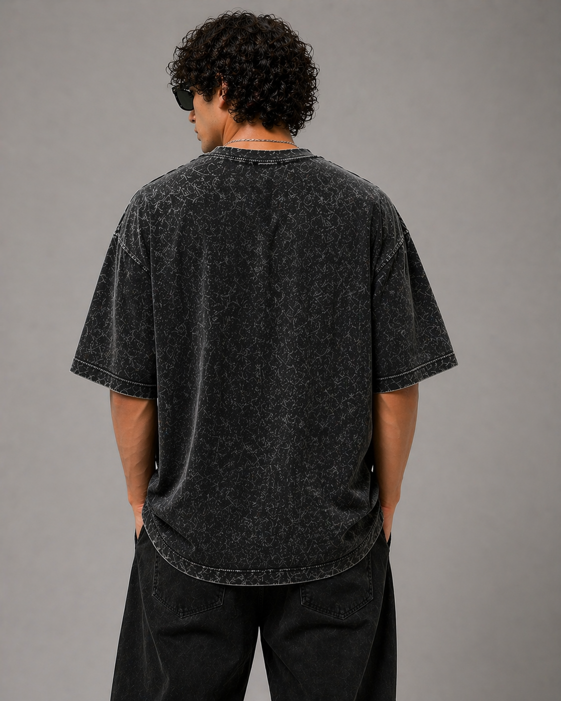 Person wearing a black acid-wash t-shirt against a gray background