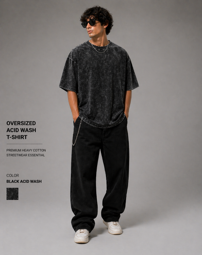 Person wearing an oversized acid wash t-shirt and black pants on a gray background