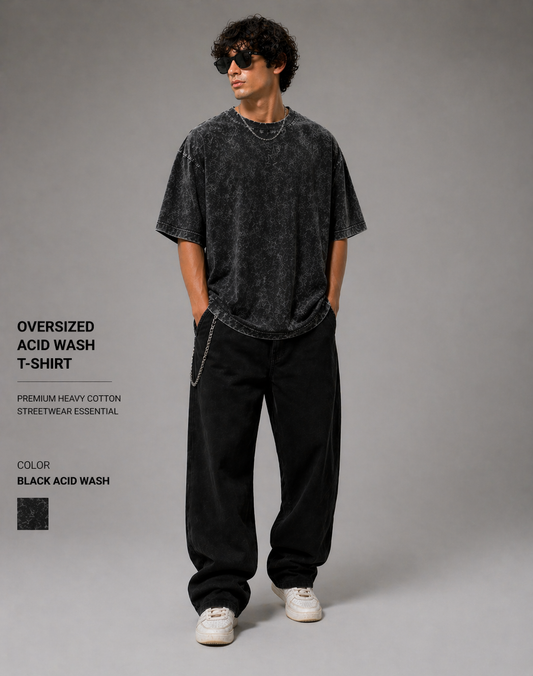 Person wearing an oversized acid wash t-shirt and black pants on a gray background