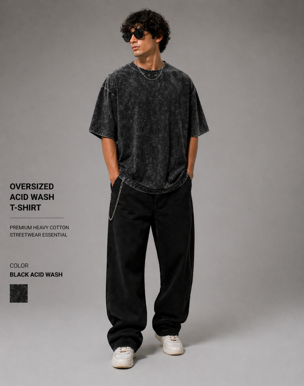 Person wearing an oversized acid wash t-shirt and black pants on a gray background