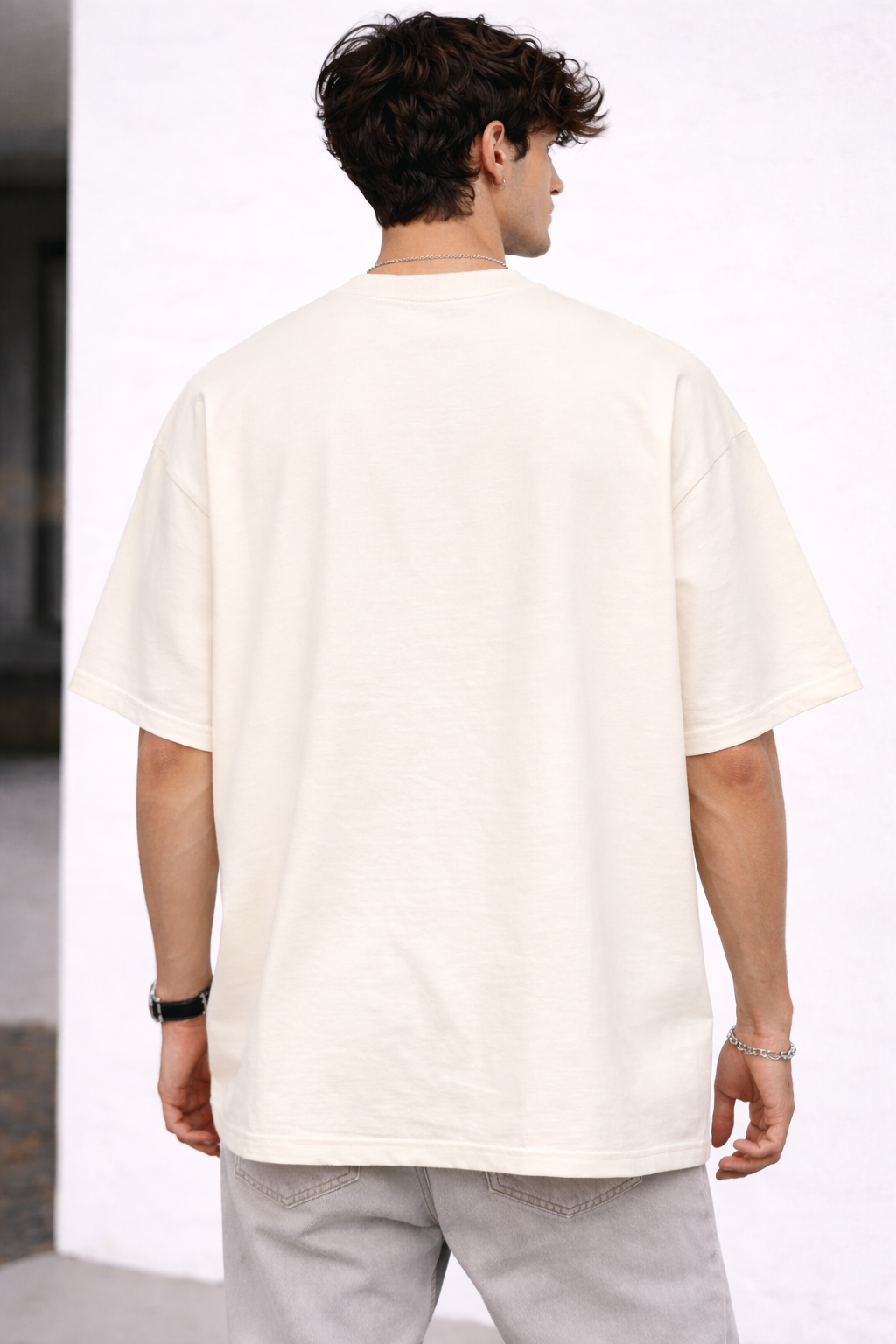 Person wearing a plain white t-shirt and light gray pants against a white background