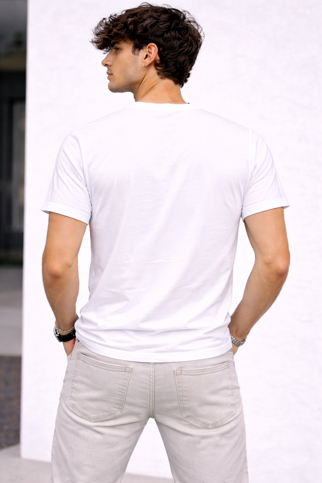 Man wearing a plain white t-shirt and light gray pants against a white background